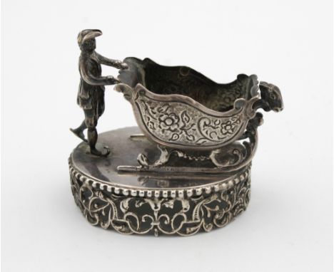A novelty Dutch silver open salt fashioned as a gentleman pushing a sled, raised on foliate pierced oval base, 7.5cm. long, w