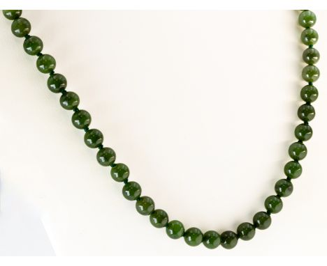 A single strand jade bead necklace, on a 9ct white gold diamond set losenge clasp, approximately 61cm long, Birmingham 1955, 