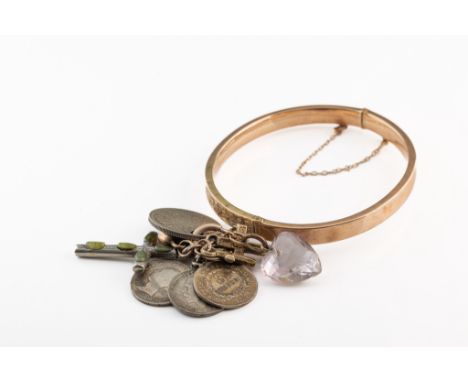 A 9ct yellow gold hinged bangle, engraved with ivy leaves, suspending three 9ct gold charms, silver cross, and white metal co