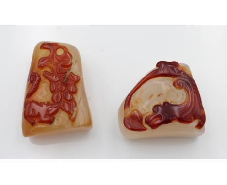 Two Chinese carved carnelian / red jade pendants, one depicting a squirrel and grapes, the other a dragon chasing it's tail, 