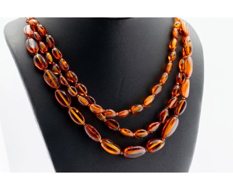 A vintage polished amber necklace, having triple rows to bottom, the beads of irregular shapes and sizes with various inclusi