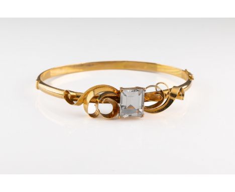 A Swedish 18k yellow gold hinged bangle, set with a step cut rock crystal, scrollwork shoulders, total gross weight approxima