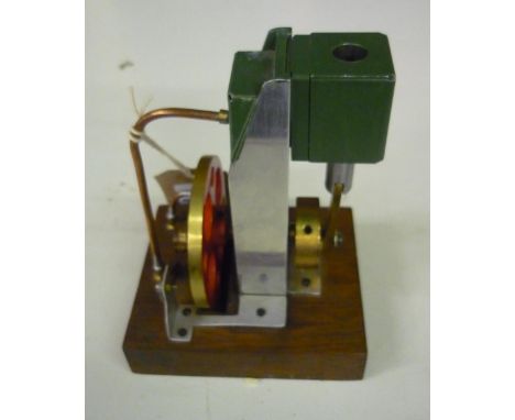 Small model of a stationary engine, with red and brass fly wheel on wooden base 