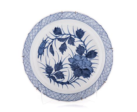 A CHINESE BLUE AND WHITE CHARGER mildly scalloped, painted with a peony amongst foliage within a diaper border, loss to ename