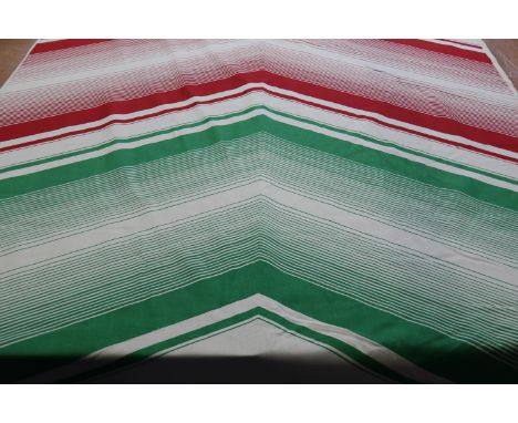 A roll of screen painted cotton fabric, the cream ground having a large red and green arrow design, 125cm wide x 28m long