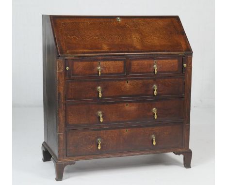 George III provincial oak bureau, circa 1800, sloping top opening to reveal a configuration of drawers and pigeonholes around