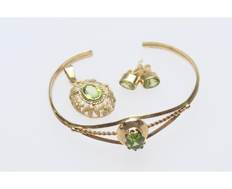 Peridot set bangle, oval cut stone in an openwork unmarked gold coloured bangle, also a pair of peridot stud earrings, in unm