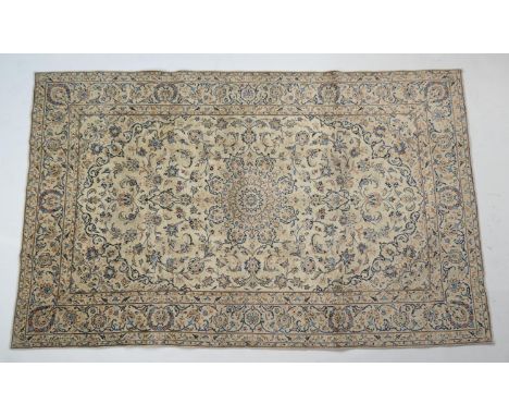 Kashan fawn ground woollen rug, the field dispersed with palmettes and foliage in light and dark blues, within a palmette bor
