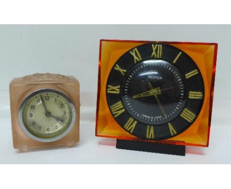 A Russian Molnija perspex cased clock and a pink opaque glass clock, small chip to glass
