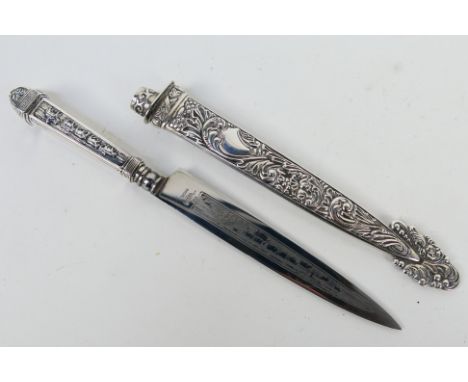 An Argentinian white metal Gaucho knife, the hilt embossed with cattle driving scene and the scabbard with foliate scrolls.No