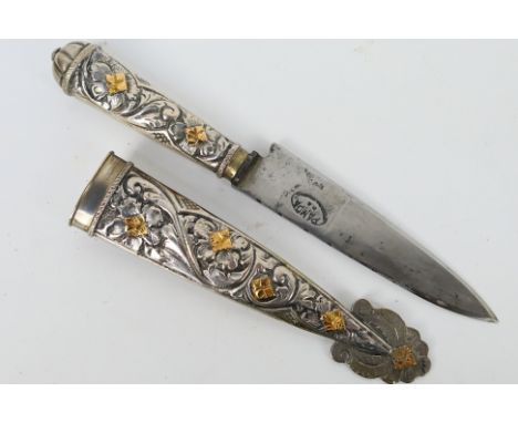 A white and gilt metal Argentinian Gaucho knife with floral decorated hilt and scabbard, the scabbard stamped 800.Note: This 