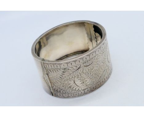 A white metal (presumed silver) bangle with inscribed foliate scrolls, approx 34.3 gm. The vendor states that this item was s