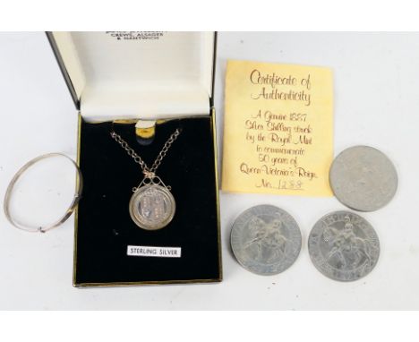 A Victorian silver shilling, 1887, in white metal mount suspended from a chain marked Sterling, a white metal bangle stamped 