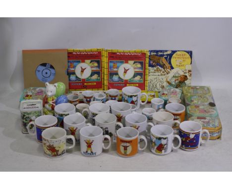 A collection of Rupert bear collectable items to include tins, money banks, ceramic cups, and similar. Lot also includes a bo