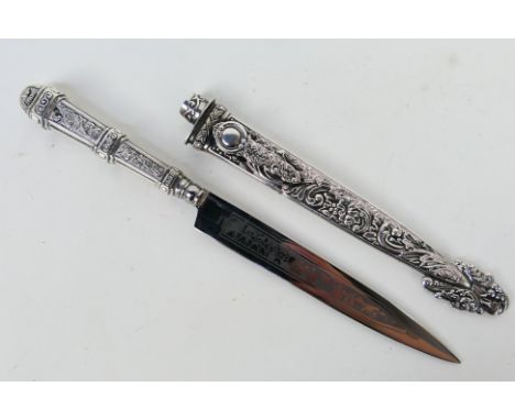 An Argentinian white metal Gaucho knife, the hilt embossed with cattle driving scene and the scabbard with foliate scrolls.No