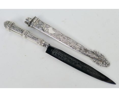 An Argentinian white metal Gaucho knife, the hilt embossed with cattle driving scene and the scabbard with foliate scrolls.No