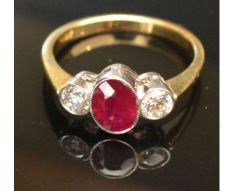 An 18ct. Yellow Gold Ruby and Diamond Three Stone Ring, with a central oval ruby flanked by diamonds within a pierced setting