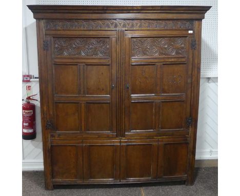 A 17th century and later carved oak hall Cupboard, the carved and moulded cornice over two large paneled doors with wrought i