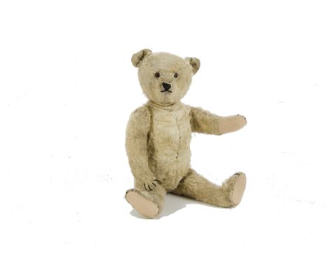 A German Teddy Bear, 1920s, with blonde mohair, replaced glass eyes and black stitching, swivel head, jointed limbs, small hu