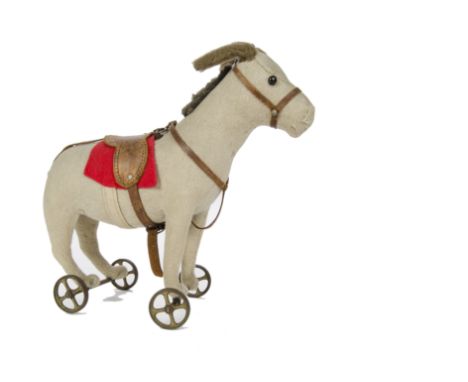 An early Steiff donkey on wheels, circa 1910, with beige burlap, black boot button eyes, original leather saddle stamped STEI
