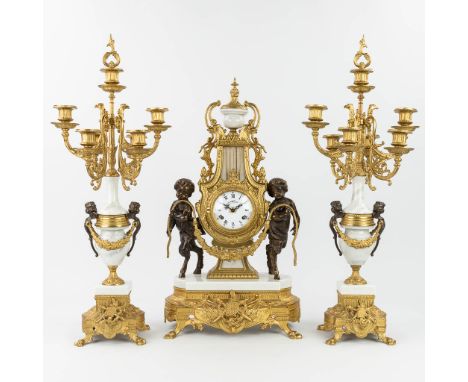 A three-piece mantle clock made of bronze and marble, Empire style, and decorated with satyr's. Around 1970. Candelabra heigh