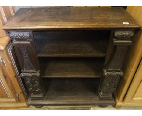 A late 19th / early 20th Century oak Gothic style open three shelf bookcase with applied moulded decoration, raised on bun fe