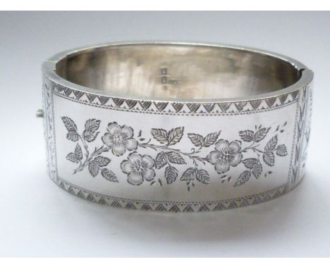 A Victorian Aesthetic Movement silver hinged-bangle, the face engraved with a floral sprig, and flanked by a pair of swallows