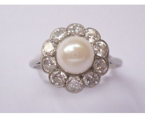 An early 20th century platinum, diamond and pearl dress ring, in a flower head cluster arrangement, the central pearl of appr