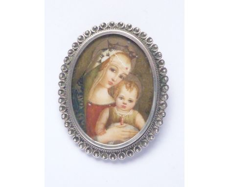 A vintage a portrait miniature brooch depicting the Madonna and child, hand-painted over ivory, in a white-metal filigree fra