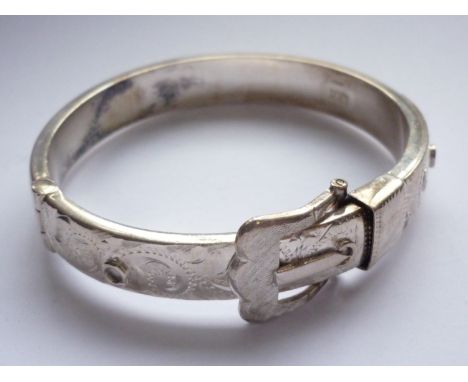 An Elizabeth II silver hinged bangle in the form of a buckled belt, bright-cut engraved with scrolling foliage, Birmingham, 1