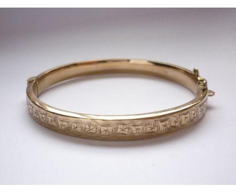 A 9ct gold hinged bangle, decorated with engraved foliage to the face, 10.2g