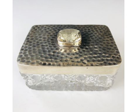 An Edwardian Arts and Crafts silver-mounted cut-glass trinket box, of rectangular section, the slip-cover planished and centr