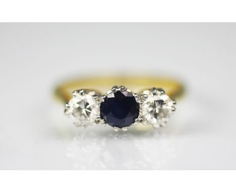 A sapphire and diamond three stone ring, the central circular sapphire flanked by a brilliant cut diamond to either side, all