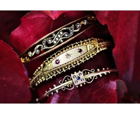 A Victorian split seed pearl set hinged bangle, stamped '9ct', a 'ruby' and diamond 9ct gold hinged bangle, Birmingham 1917 a