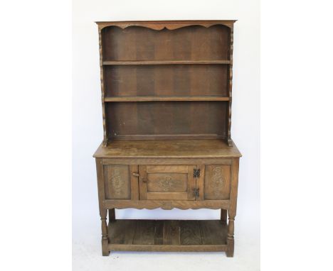 A 1920's carved oak dresser, with two shelves on base with cupboard door and pot shelf, on turned legs, 166cm H x 95cm W x 38