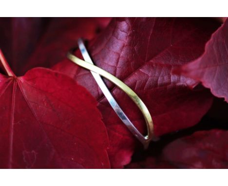 A bi-colour gold hinged bangle, the yellow and white strands of entwined form, integral clasp, stamped 'Italy 375', weight 10