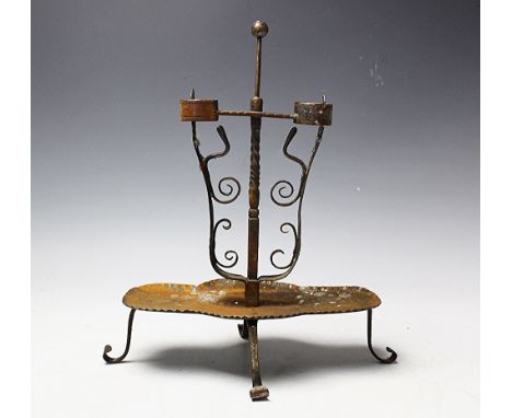 A folk art wrought iron twin branch candle stick, with scroll springs, on shaped platform and scroll feet, 36cm high