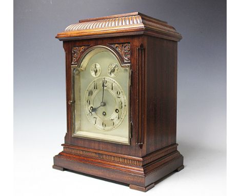 A late Victorian carved walnut eight day mantel clock, with silvered Arabic chapter ring below two subsidiary dials, with mov