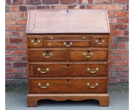 A George III style oak bureau, with fall enclosing a fitted interior, over three short, two further short and two long gradua