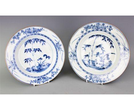 A pair of 18th century Chinese porcelain plates, each circular blue and white plate decorated with a landscaped scene within 