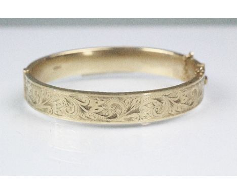 A 9ct yellow gold hinged bangle, Birmingham 1991, sponsors mark 'H.G & S', half engraved and with attached safety chain (brok