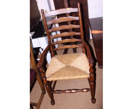A pair of oak ladder back elbow chairs with rush envelope seats, on turned and stretchered supports