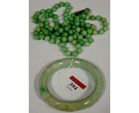 A pale and mottled green Chinese carved jade bangle; together with a jade beaded necklace (2)  Condition Report / Extra Infor