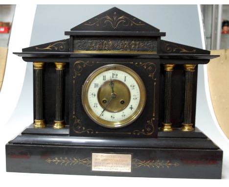 A circa 1900 slate mantel clock of architectural outline having presentation plaque and striking movement