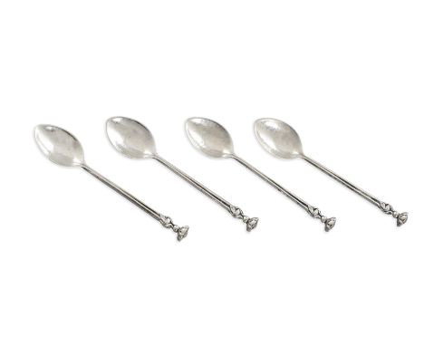 A SET OF FOUR 'OMAR RAMSDEN' SILVER COFFEE SPOONS, London 1908, each with flowerhead finial and hammered bowls. Each 11cm lon