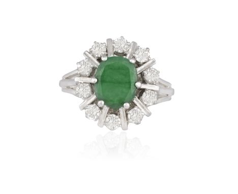 AN EMERALD AND DIAMOND CLUSTER RING, the oval-shaped emerald within a six-claw setting, to a surround of brilliant-cut diamon