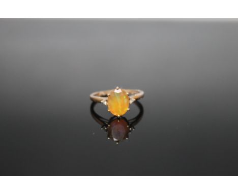 A 9 CARAT YELLOW GOLD DRESS RING, set with a yellow opaque stone and two small diamonds, ring size L 