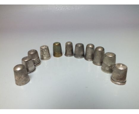 A COLLECTION OF WHITE METAL THIMBLES, to include sterling and hallmarked silver examples, together with a brass thimble (11)