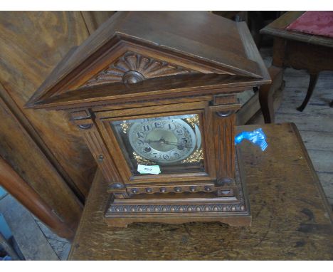 Ornate wooden mantel clock of Victorian era, heavily decorated with metal dial strking on the half and the hour