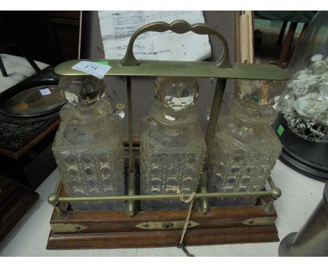 Oak tantalus with brass handle and workings containing 3 glass decanters having original lock and key